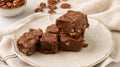 Squares of Grandma's chocolate pecan fudge on a cream plate