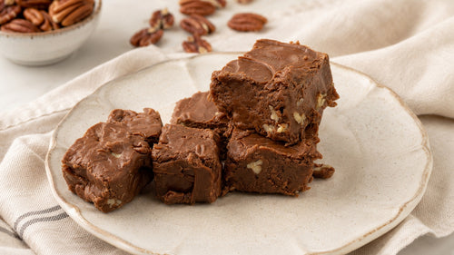 Squares of Grandma's chocolate pecan fudge on a cream plate