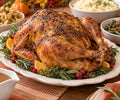 Terri's golden roasted Thanksgiving turkey on a platter with herbs, oranges and cranberries